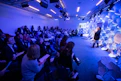 woman making speech in front of people sitting on individual chairs