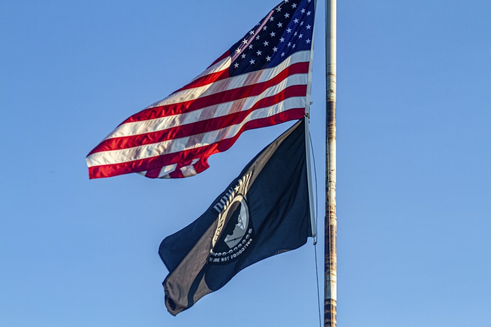 U.S. flag flying over blue and white flag in pole