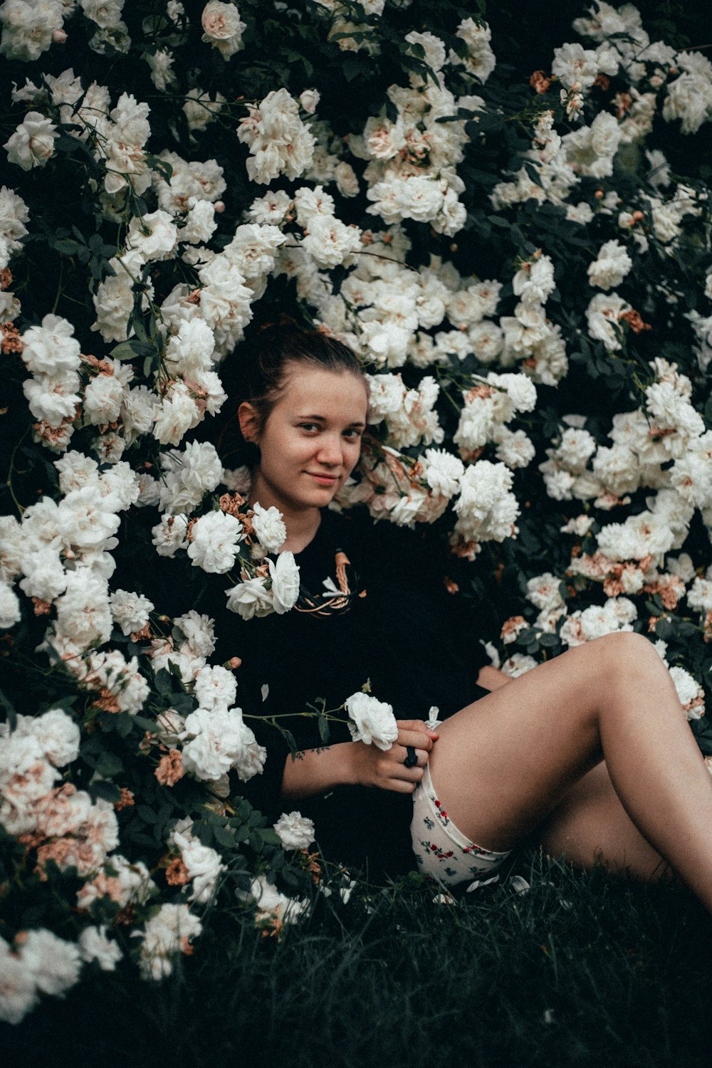 꽃으로 둘러싸인 풀밭에 앉아있는 여자