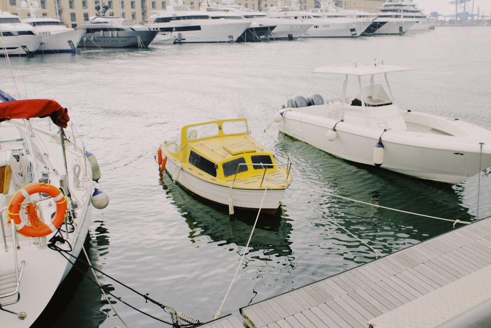 Weiße Yacht in der Nähe von weißer und gelber Yacht neben Dock