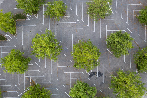 Aerial view of a parking lot with freshly painted parking space lines under bright sunlight.