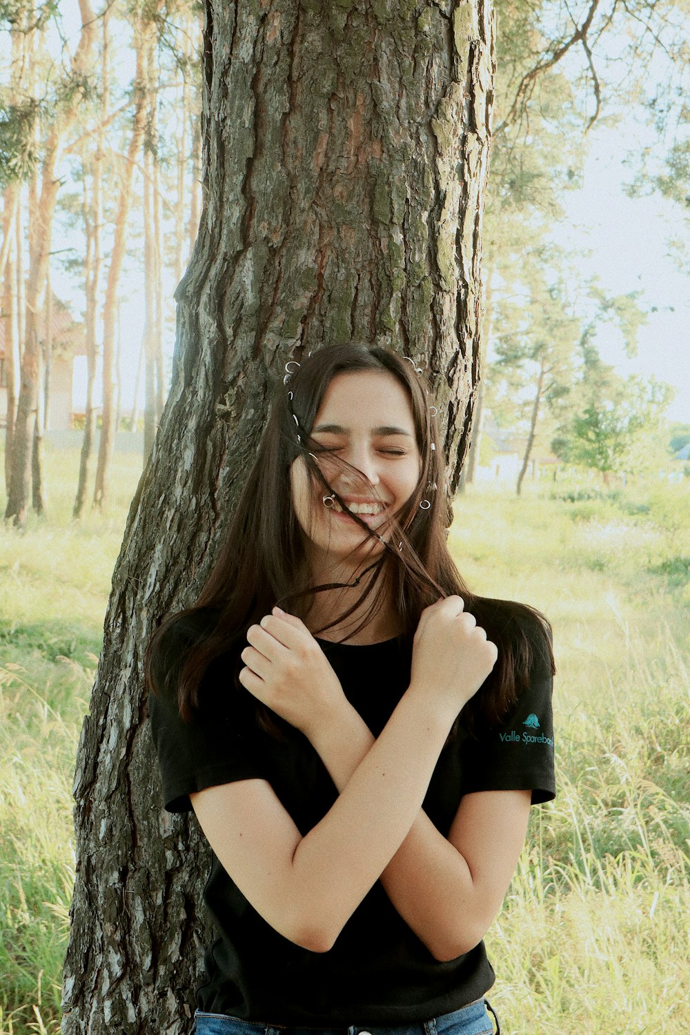 woman in black leaning on a tree