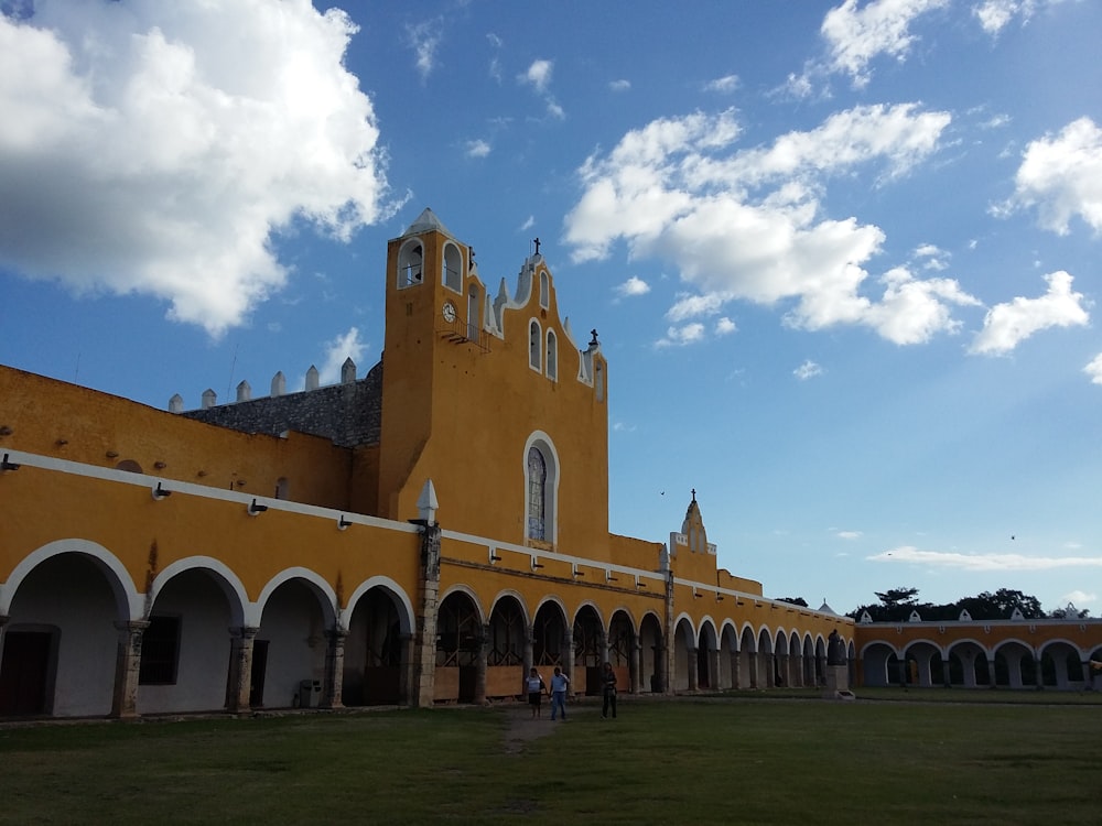 people walking near concrete church under blue and white skies