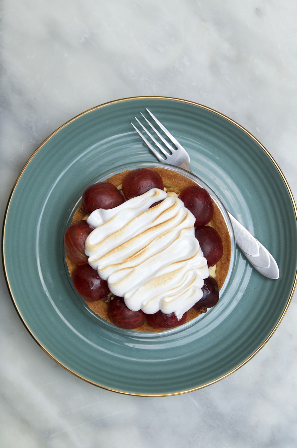 white sauce topped pastry in teal round ceramic plate