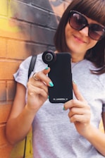 A smiling content creator filming a casual lifestyle video with a smartphone.