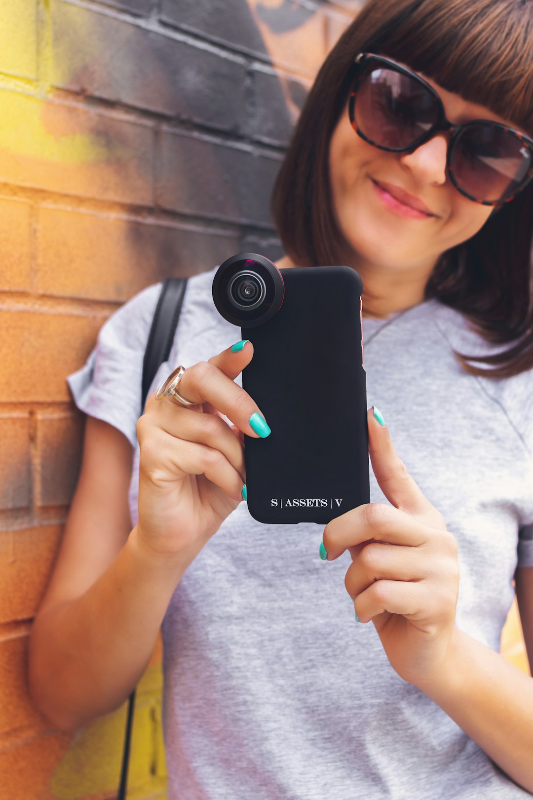 woman leaning on wall while holding phone