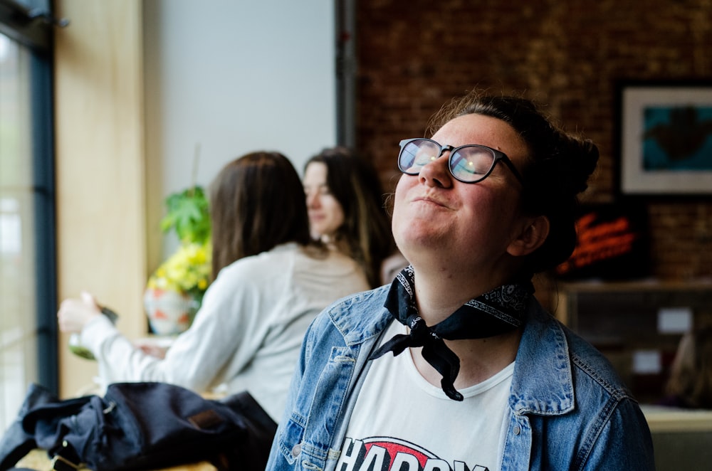 donna che indossa giacca di jeans blu seduta e sorridente mentre chiude gli occhi