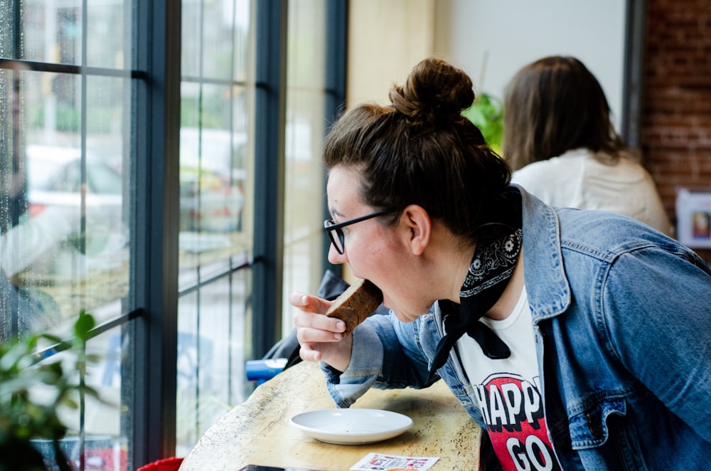 woman eating cake in front of window