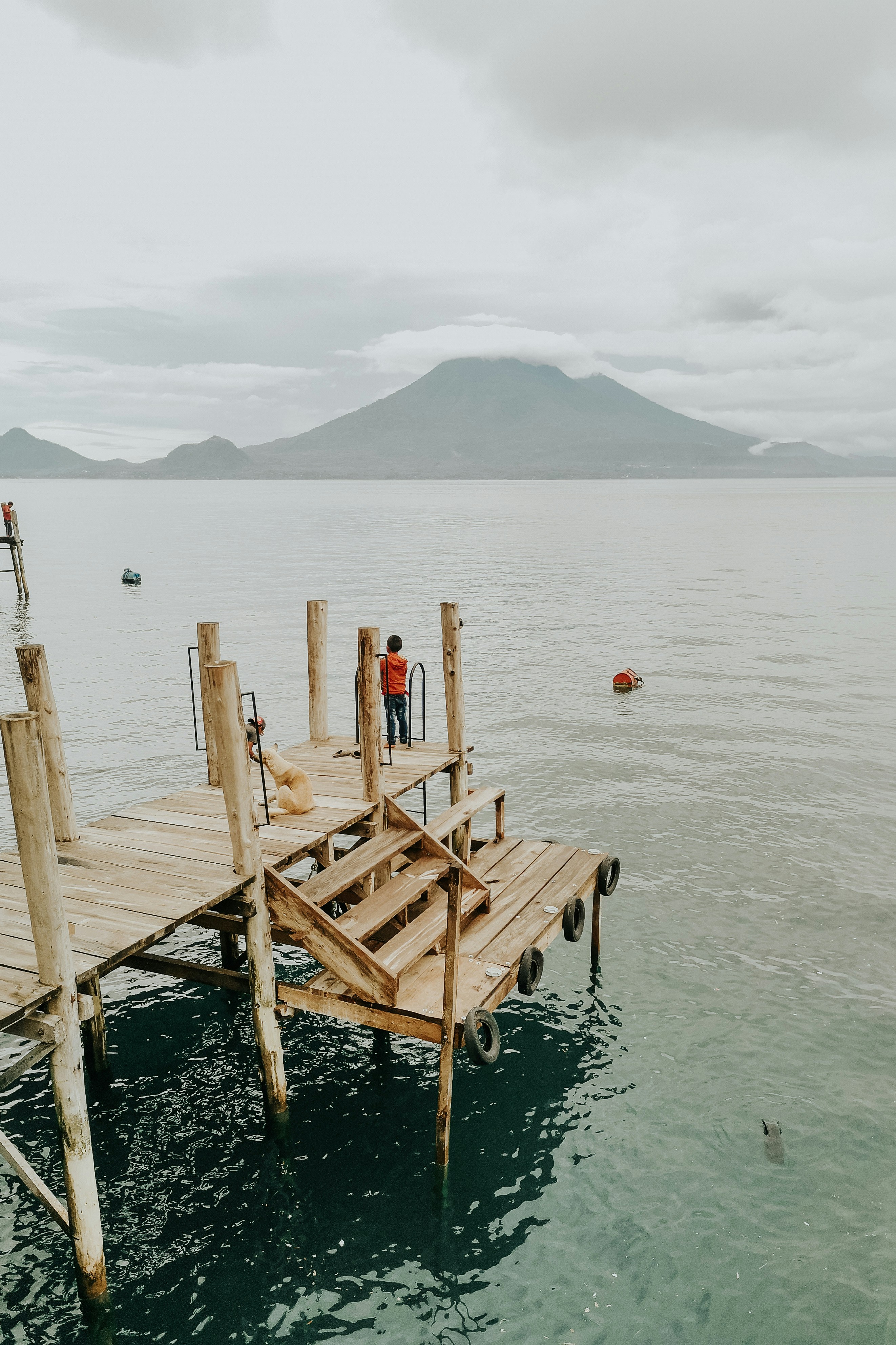 person standing on wooden dock at the lake