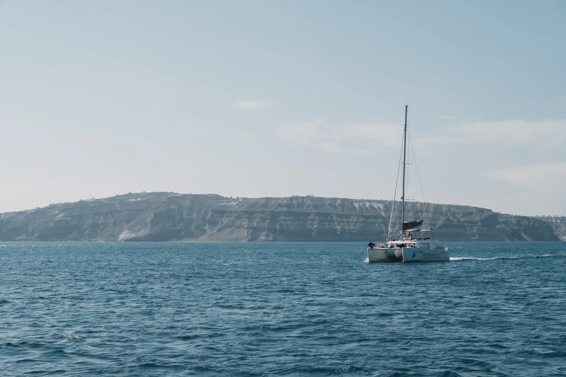 Luxury private catamaran sailing the Santorini caldera at sunset