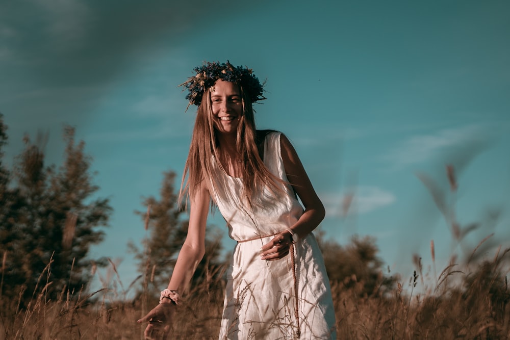 smiling woman wearing flower crown standing on brown grass field