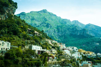 A panoramic view of a peaceful Niolu village nestled among lush green mountains under a clear blue sky.