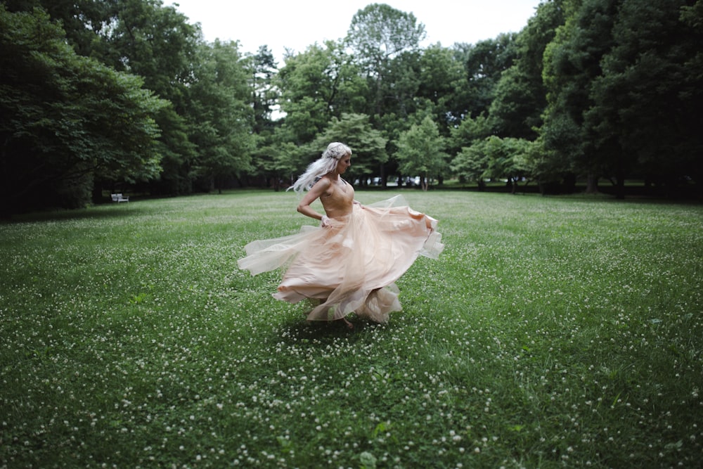 woman standing and dancing on green field