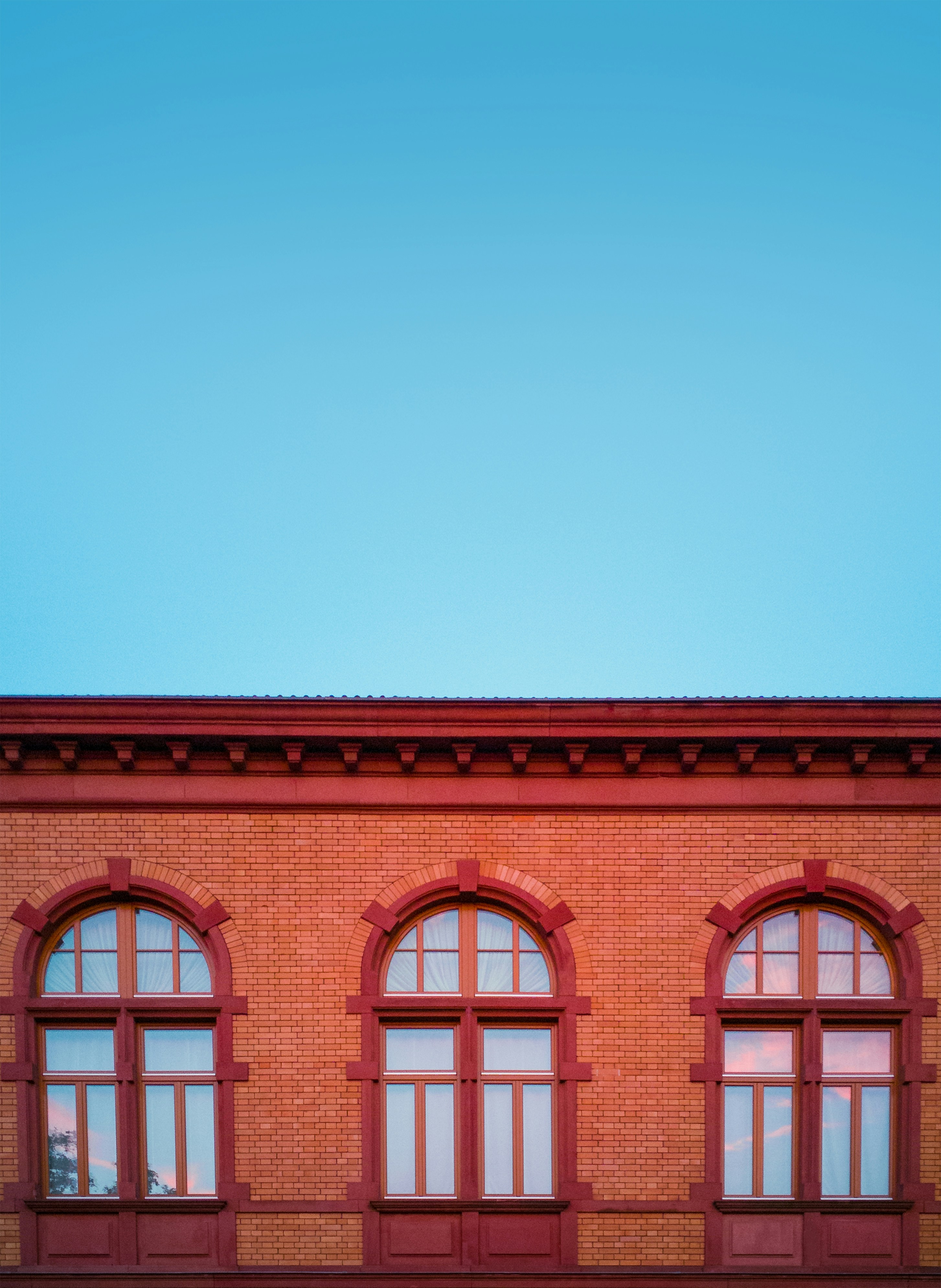red and brown concrete building with three glass windows under blue sky