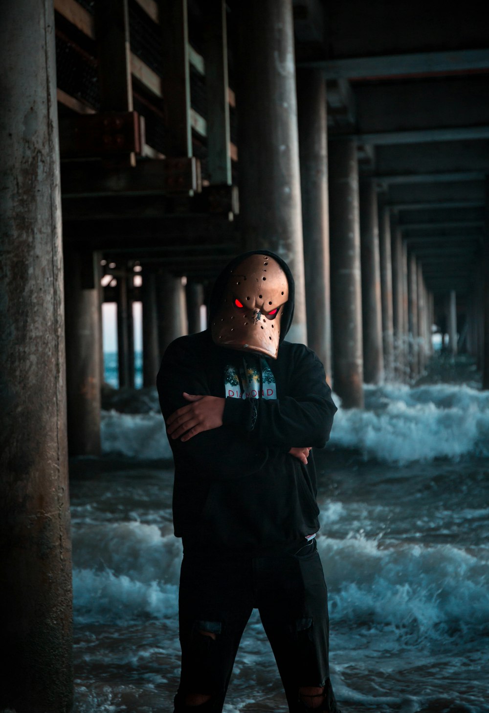 man wearing mask while standing under a bridge in the sea