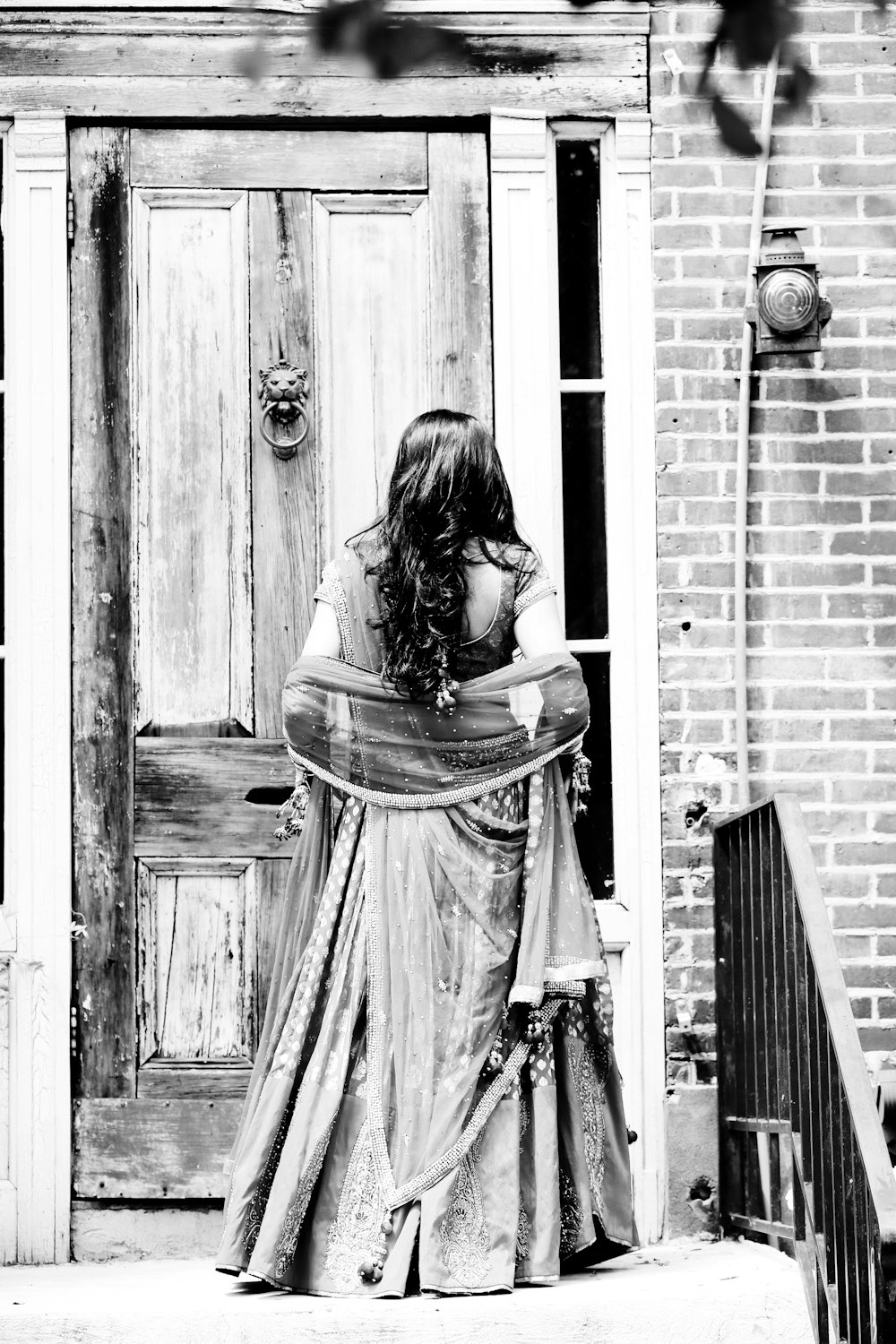 woman wearing dress facing at the door grayscale photography