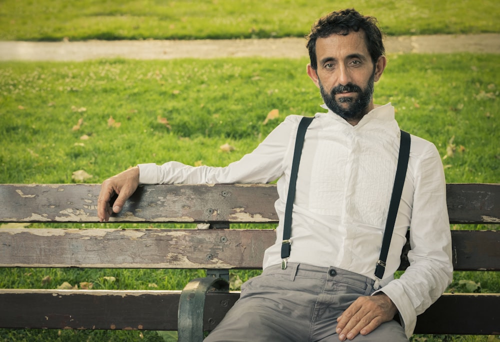 man wearing white dress shirt sitting on outdoor bench