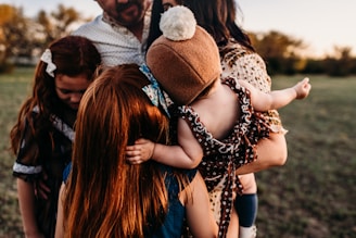 woman carrying baby being hugged by man and two girls