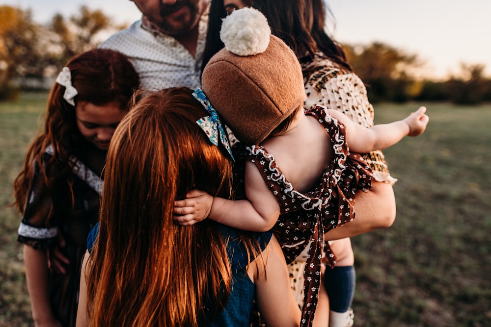 woman carrying baby being hugged by man and two girls