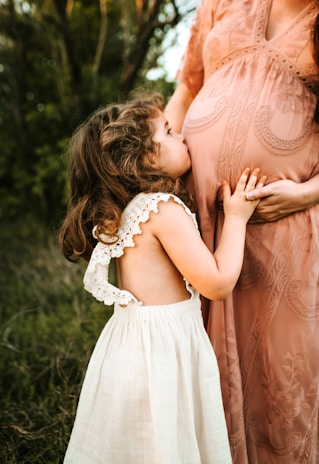 child kissing woman's tummy maternity
