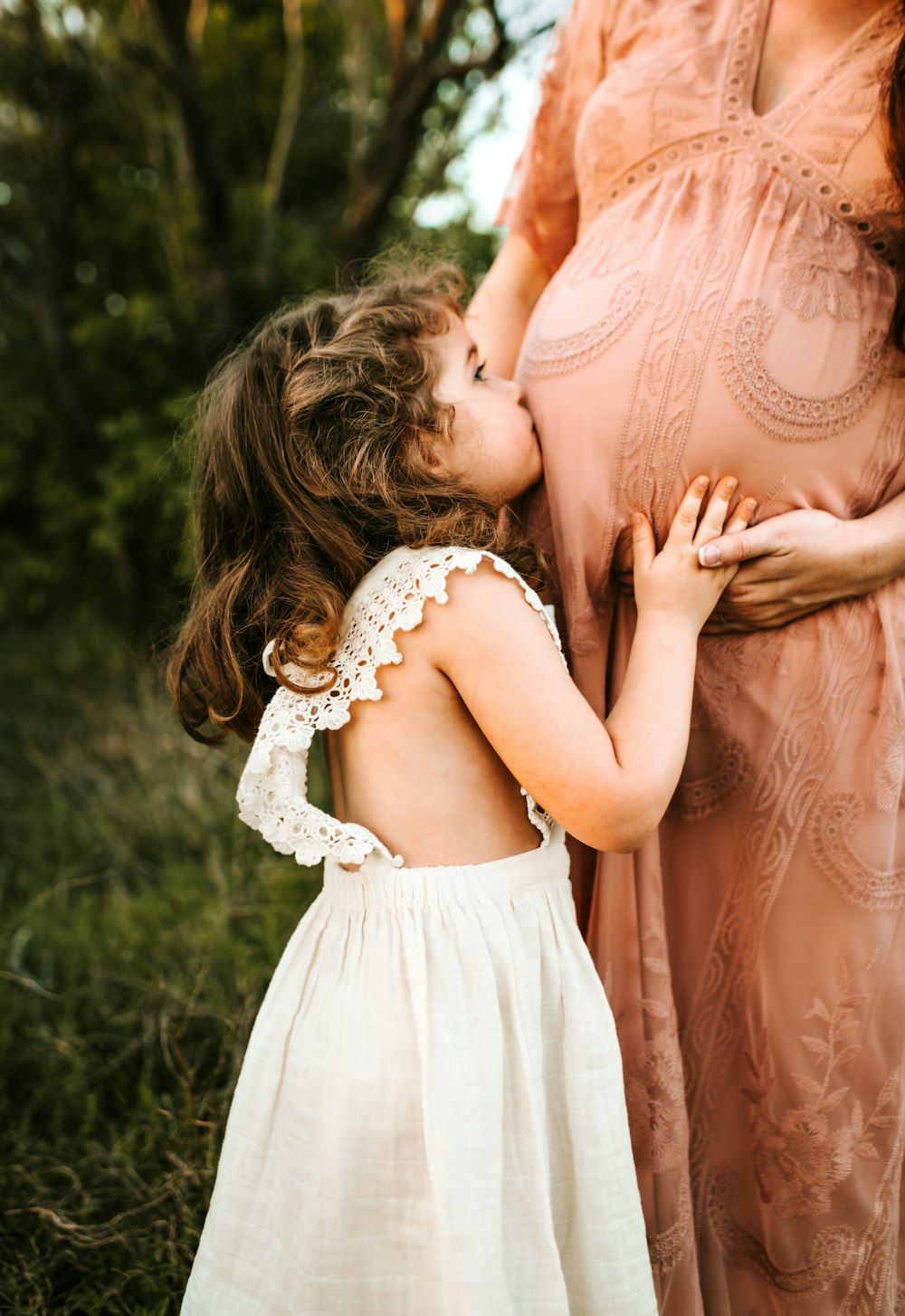 child kissing woman's tummy