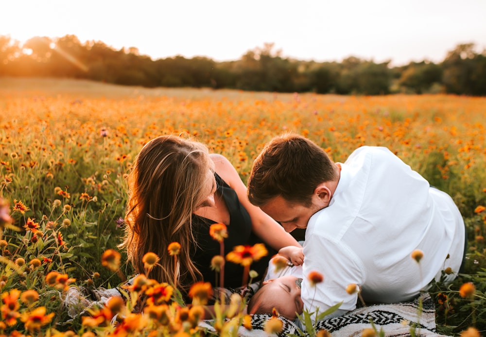 family of three lying on bed of flowers