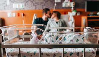 baby sleeping on front of couple on bed