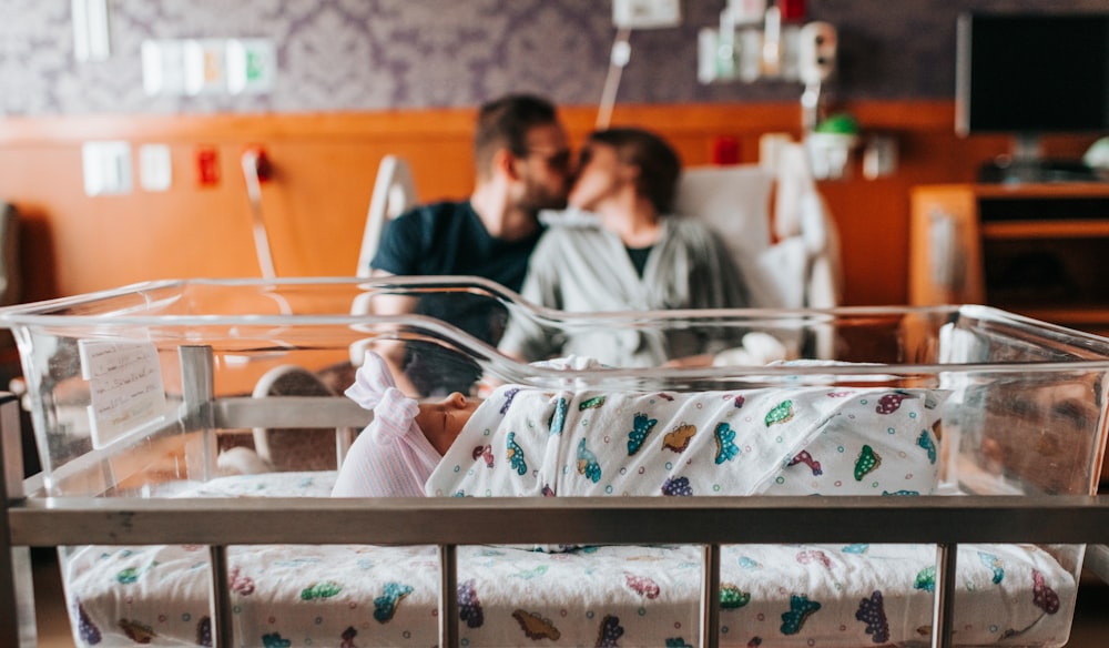 baby sleeping on front of couple on bed