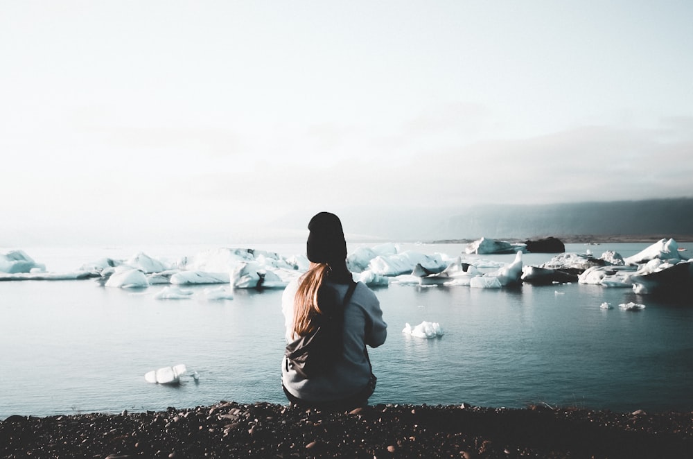 unknown person sitting near body of water