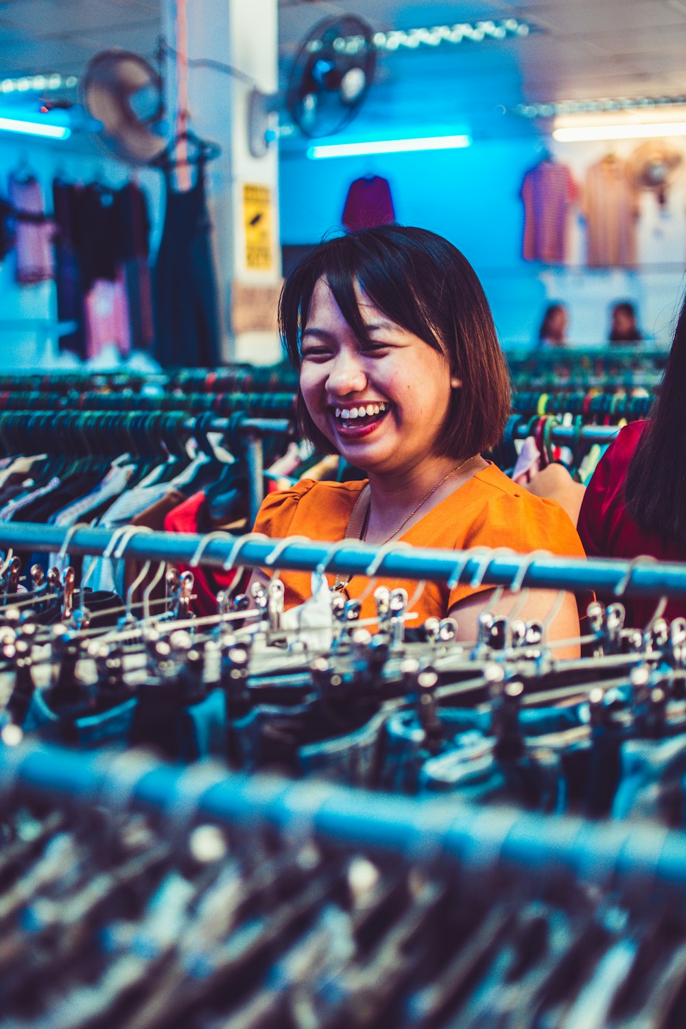 woman smiling standing beside clothes