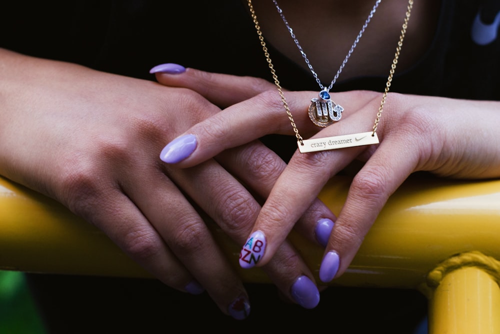 person with purple manicure holding yellow rail