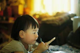 Close-up of a child’s hands holding a bowl of nutritious food, with a gentle smile in the background.