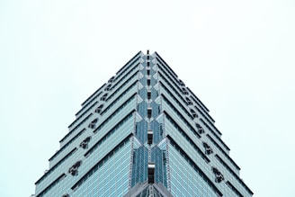 A sleek, modern 12-story commercial tower rising amidst the city skyline on a clear day.