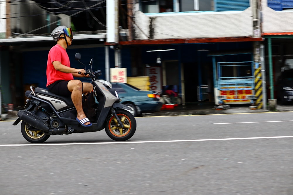man wearing red shirt riding on motor scooter