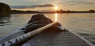 A serene view of a paddleboard on calm turquoise waters near Crete's coastline at sunset.