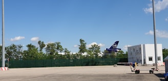 Ramp agents guiding an aircraft into position with hand signals under a clear blue sky.
