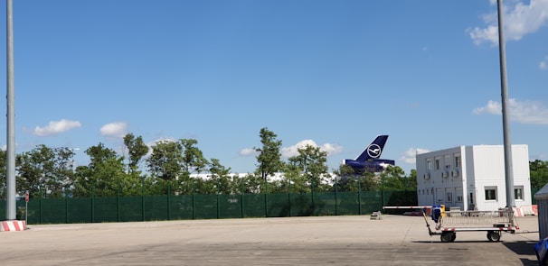 Ramp agents guiding an aircraft into position with hand signals under a clear blue sky.