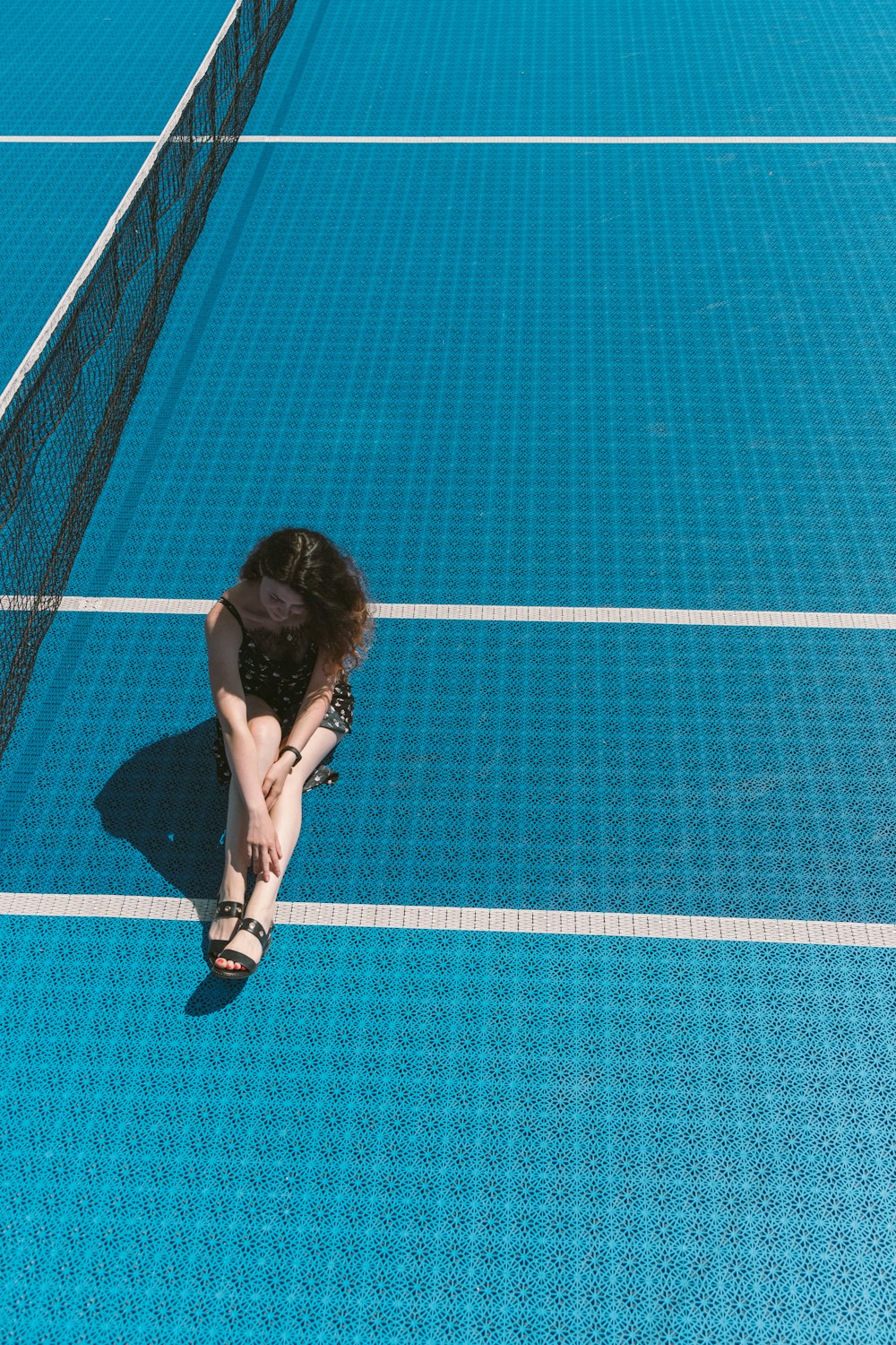 Frau sitzt auf einem Tennisplatz
