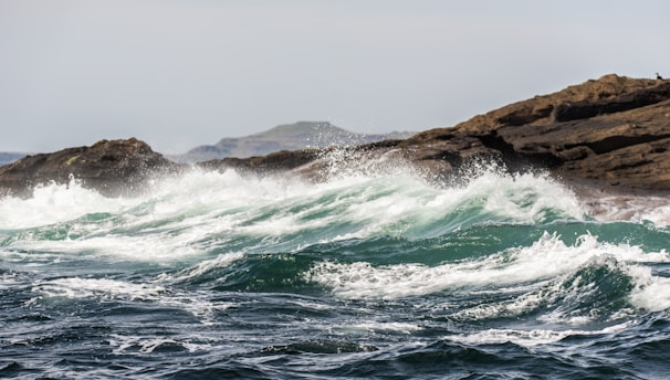 white wave foams breaking on brown rocks in beach