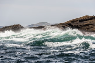 Film production company shot of white waves breaking on brown rocks at a beach