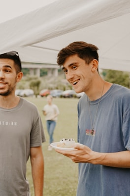 Smiling people sharing a meal outdoors in a green environment.
