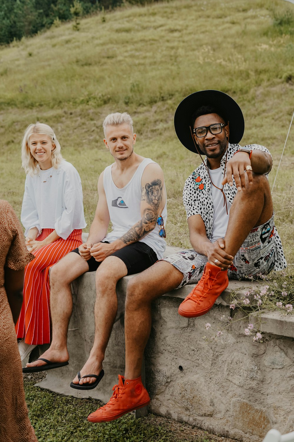 two men and 1 woman sitting on concrete bench