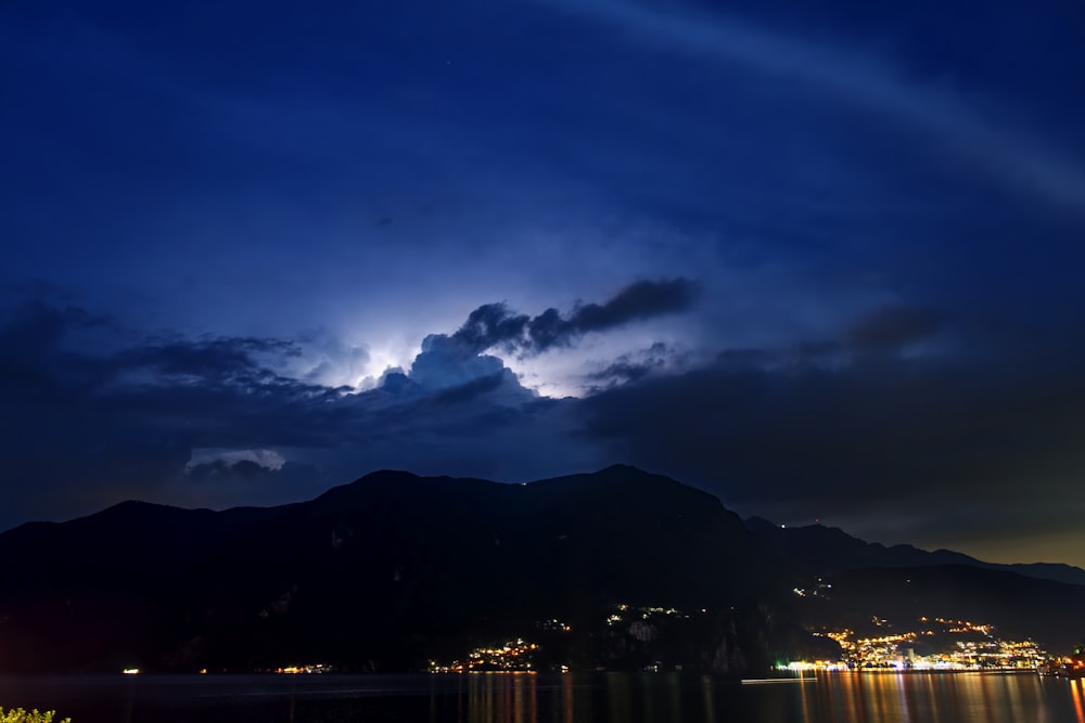 silhouette photography of mountain under cloudy sky during nighttime