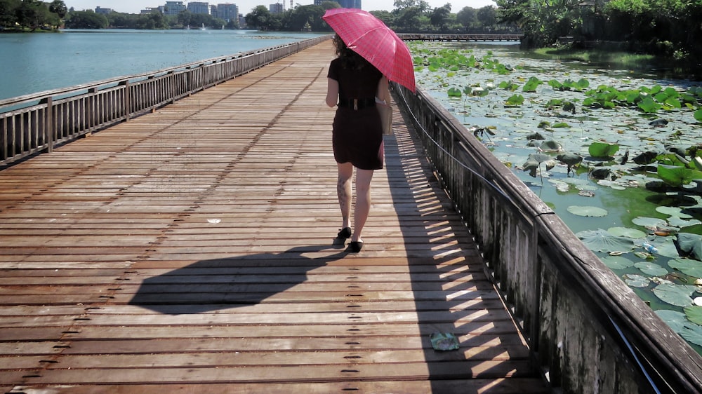 Frau im schwarzen Kleid geht auf Holzbrücke