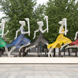 five running women wearing different dresses holding torch statue