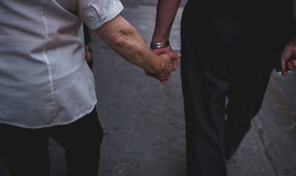 man and woman holding hands while walking during daytime