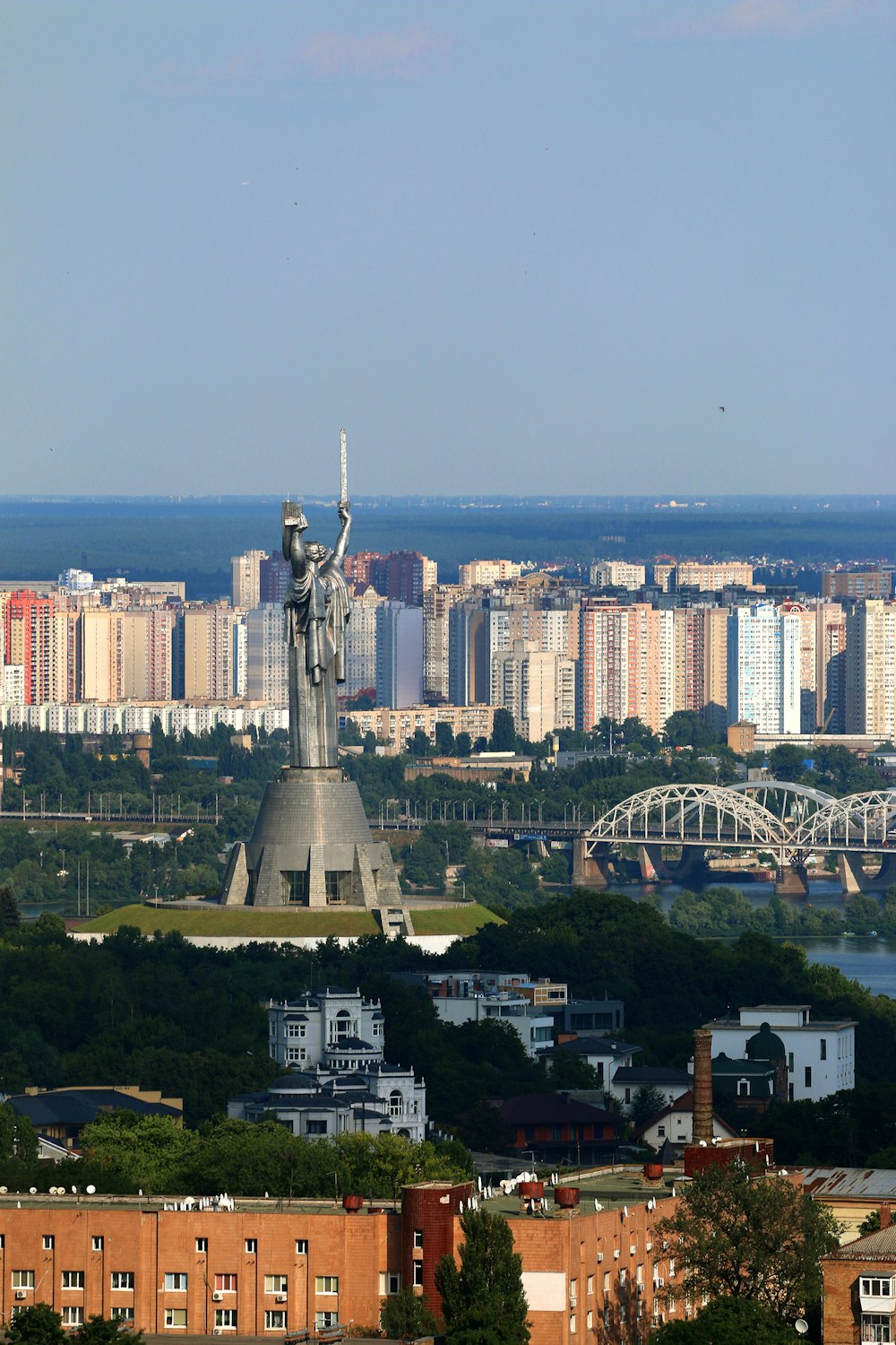 aerial photography of statue near arch bridge during daytime