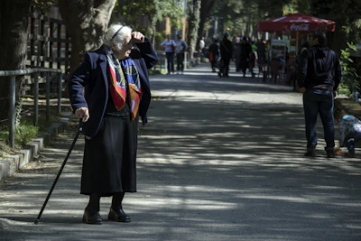 Senior man walking confidently with a cane on a sunny path.