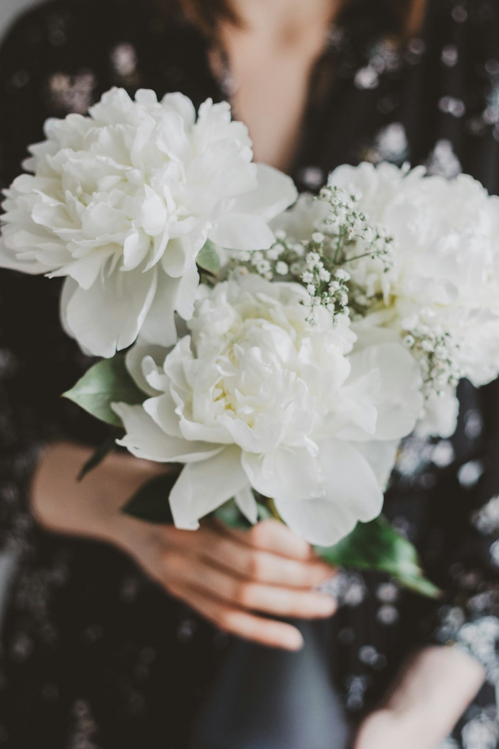 shallow focus photo of person holding white flowers