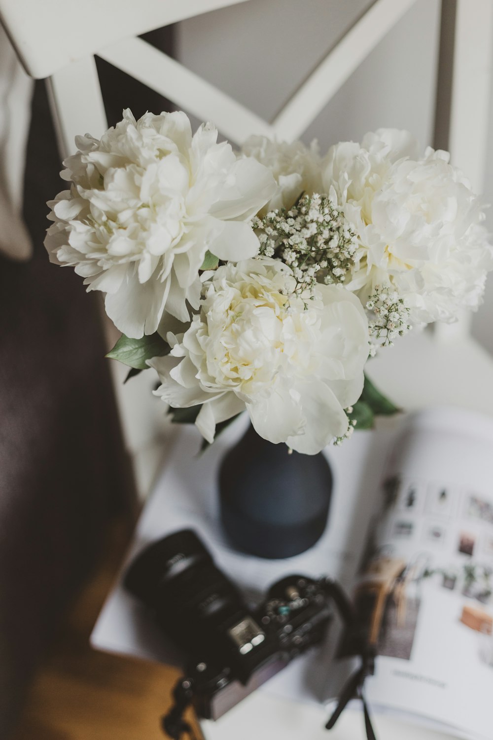 테이블 위에 검은 꽃병에 흰 모란 꽃